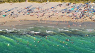 Sarasota County, ABD 'deki kalabalık Nokomis plajının yüksek açılı görüntüsü. Birçok insan tatilin tadını çıkarıyor. Okyanus suyunda yüzmek ve gün batımında sıcak Florida güneşinde dinlenmek..