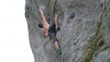 Güçlü erkek tırmanıcı kayalık dağın dik duvarına tırmanıyor. Sporcu zor yolu aştı. Ekstrem spor hobisi konsepti.