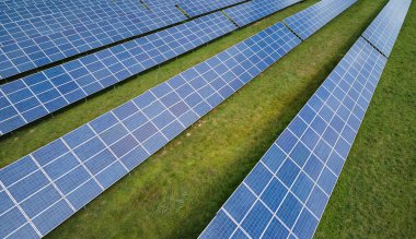 Temiz elektrik enerjisi üretmek için sıra sıra güneş fotovoltaik panelleri olan sürdürülebilir büyük elektrik santralinin havadan görünüşü. Sıfır emisyonlu yenilenebilir elektrik kavramı.