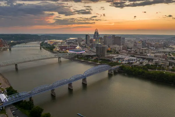 stock image Cincinnati city, Ohio, USA with bridge highway traffic driving cars in downtown district. American city skyline with brightly illuminated high commercial buildings at sunset.