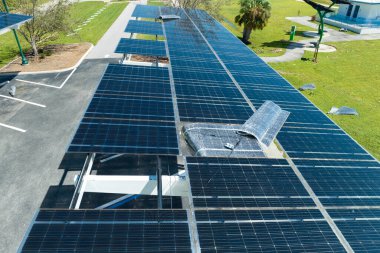 Park alanının gölgesinde, temiz enerjinin etkin üretimi için park etmiş arabaların güneş panellerine rüzgar hasarı.