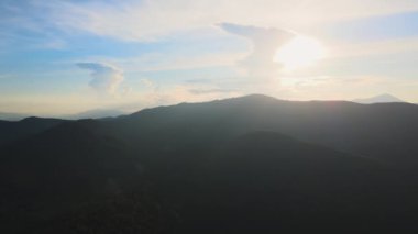 Gün batımında puslu tepeleri ve sisli vadisi olan güzel dağ panoramik manzarası.