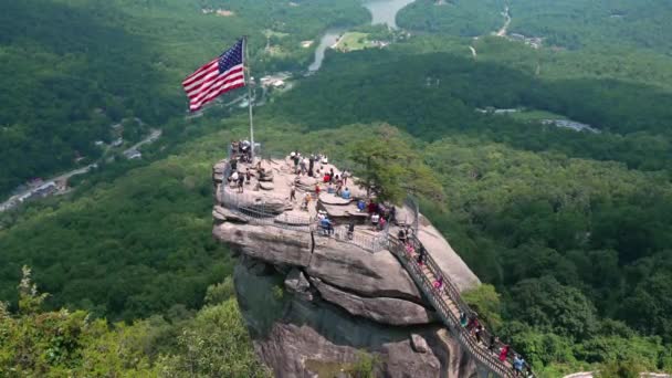 在美国北卡罗莱纳州的Chimney Rock州立公园 Chimney Rock带着奉承的美国国旗和许多游客 阿巴拉契亚山脉旅游胜地 — 图库视频影像