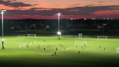 Geceleri çimen stadyumunda futbol oynayan insanlarla dolu halka açık spor parkı. Aktif yaşam konsepti.