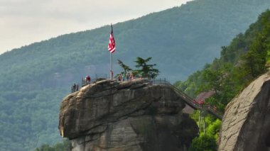 Amerikan ulusal bayrağını öven Chimney Rock ve Kuzey Carolina 'daki Chimney Rock State Park' ta bir sürü turist. Appalachian dağlarında gidilecek yer