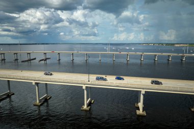 Barron Collier Bridge and Gilchrist Bridge in Florida with moving traffic. Transportation infrastructure in Charlotte County connecting Punta Gorda and Port Charlotte over Peace River. clipart