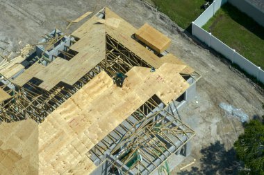 Florida 'nın banliyö bölgesinde ahşap iskeleti olan bitmemiş bir konutun çatı inşaatında çalışan inşaatçılar. Konut geliştirme kavramı.