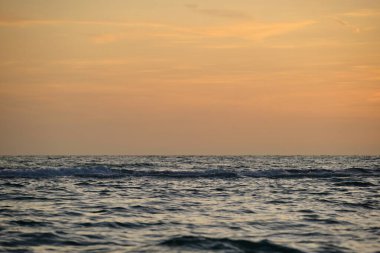 Dramatic red ocean waves at sunset with soft evening sea dark water.