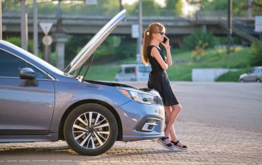 Kaputu açık halde arabasının yanında duran çaresiz bir kadın cep telefonundan yardım için yol servisini arıyor. Genç bayan sürücünün aracıyla ilgili sorunları var.