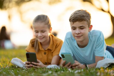 Arkadaşlarıyla cep telefonuyla mesajlaşan mutlu çocukların portresi