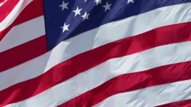 Mavi gökyüzüne karşı rüzgarda dalgalanan Amerikan ulusal bayrağı. ABD 'li yıldızlar ve çizgiler demokrasinin sembolü olarak gösterildi.