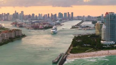 Güney Sahili yakınlarındaki ana kanaldan Miami limanına giden lüks bir yolcu gemisi. Sahildeki oteller ve konutlar ve şehir merkezindeki yüksek gökdelen kuleleri..