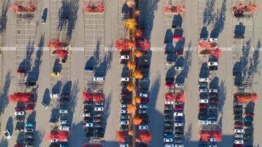 Bir alışveriş merkezinin önündeki otoparkta park edilmiş birçok arabanın üst görüntüsü. Tüketim ve piyasa ekonomisi kavramı.
