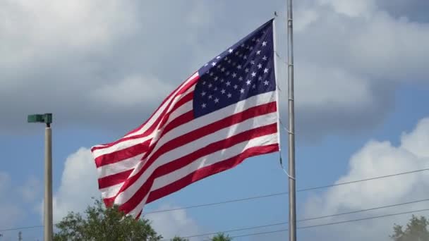 アメリカの国旗が青空に向かって風を吹いている 米国の星とストライプは民主主義のシンボルとしてバナーをばらばらにしました — ストック動画