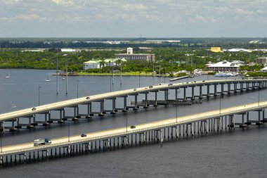 Barron Collier Bridge and Gilchrist Bridge in Florida with moving traffic. Transportation infrastructure in Charlotte County connecting Punta Gorda and Port Charlotte over Peace River. clipart