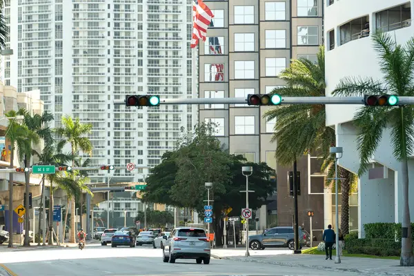 American street with driving cars at intersection with traffic lights in Miami, Florida. USA transportation.