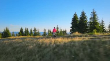 Renkli gündoğumunda dağ yolunda koşucu eğitimi. Dağlık yolda tek başına koşan bir adam.