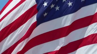 ABD ulusal bayrağı mavi gökyüzüne karşı rüzgarda dalgalanıyor. Amerikan yıldızları ve çizgileri demokrasinin sembolü olarak gösterildi..