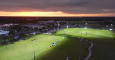 Gün batımında çimen stadyumunda futbol maçına katılan insanların olduğu parkın havadan görüntüsü. Aktif yaşam konsepti.