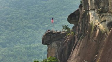 Chimney Rock 'ın hava görüntüsü, Amerikan ulusal bayrağı ve birçok turist Kuzey Carolina' daki Chimney Rock State Park 'ta. Appalachian dağlarında gidilecek yer