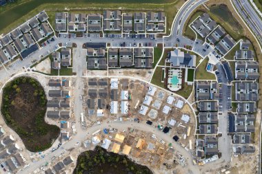 İnşaat halindeki uygun fiyatlı evlerin bitmemiş ahşap çerçevelerinin havadan görünüşü. Amerikan banliyölerinde konut geliştirme. ABD 'de emlak piyasası.