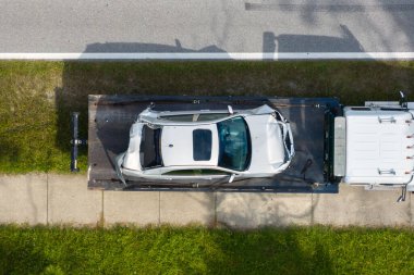Tow truck loading crashed car on accident site. Emergency services personnel and vehicles responding to vehicle crash on American street. First responders helping on road in the USA.