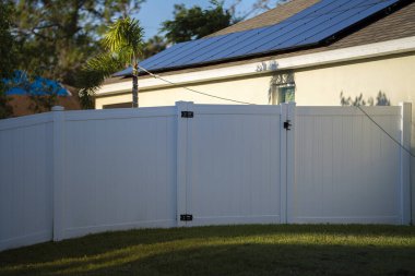 Bahçeyi çevreleyen yeşil çimlerde bahçe koruması ve mahremiyet için beyaz vinil çitler..