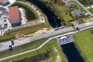 Yol çalışması alanındaki inşaat kamyonları. Sel suları asfaltı yıktıktan sonra nehir tarafından yıkılan hasarlı yol köprüsünün yeniden inşasındaki barikat. Yıkılmış ulaşım altyapısının yeniden inşası.