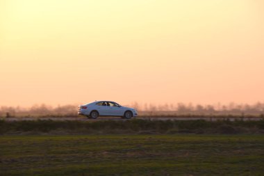 Gün batımında şehir içi yolda hızlı giden bir araba. Akşamları otoyol trafiği.