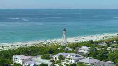 Rich neighborhood with expensive vacation homes and white lighthouse on ocean shore in Boca Grande, small town on Gasparilla Island in southwest Florida. Wealthy waterfront residential area.