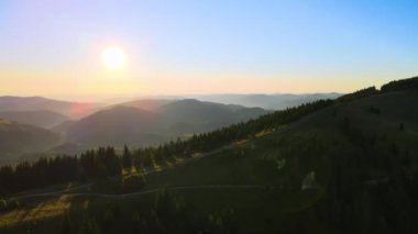 Offroad yolu tepenin üstünden geçiyor. Parlak batan güneşle aydınlanan karanlık toprak yol. Vahşi dağ ormanlarında gün batımı manzarası inanılmazdır. Güzel doğa manzarası.