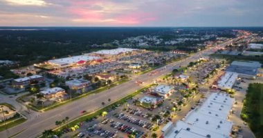 North Port, Florida 'daki American geniş yolu ve alışveriş merkezi plazası. Gün batımında araba sürerek şehir trafiğini aydınlattı. ABD ulaştırma altyapı kavramı