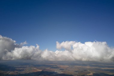 Dünya 'nın yüksek irtifasındaki uçak penceresinden hava manzarası beyaz kabarık kümülüs bulutlarıyla kaplı..