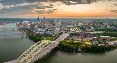 Ohio, ABD 'nin Cincinnati şehrinin şehir merkezindeki köprüde araç kullanan otoyol trafiği. Gece vakti ışıl ışıl parlayan yüksek ticari binalarla Amerikan şehri silueti.