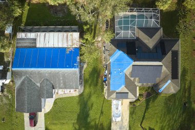 Ian Kasırgası, asfalt kiremitleri değişene kadar yağmur suyuna karşı koruyucu plastik muşambayla kaplı çatılara zarar verdi. Doğal afetten sonra.