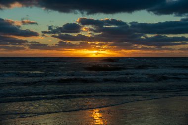 Ocean sunset landscape with soft evening sea water waves crushing on sandy beach.