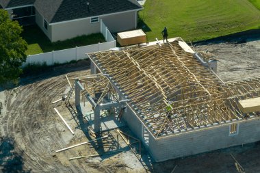 Florida kırsal kesiminde ahşap iskeleti olan bitmemiş bir banliyö evinin çatı inşaatında çalışan profesyonel müteahhitler. Amerika 'da konut geliştirme kavramı.