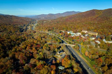 Aerial view of I-40 freeway in North Carolina leading to Asheville through Appalachian mountains in golden fall with fast moving trucks and cars. Interstate transportation concept.
