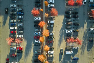 Bir alışveriş merkezinin önündeki otoparkta park edilmiş birçok arabanın üst görüntüsü. Tüketim ve piyasa ekonomisi kavramı.