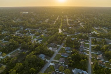 Florida 'daki yeşil palmiye ağaçları arasındaki banliyö özel evlerinin hava manzarası günbatımında sakin kırsal bölge.