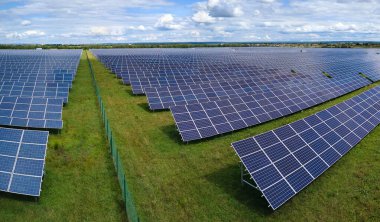 Temiz elektrik enerjisi üretmek için sıra sıra güneş fotovoltaik panelleri olan sürdürülebilir büyük elektrik santralinin havadan görünüşü. Sıfır emisyonlu yenilenebilir elektrik kavramı.