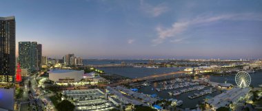 Aerial view of Skyviews Miami Observation Wheel at Bayside Marketplace with reflections in Biscayne Bay water and high illuminated skyscrapers of Brickell, citys financial center at night.