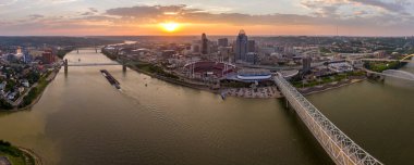 Ohio, Cincinnati 'nin şehir merkezi, gün batımında köprüde araba trafiği ve aydınlık gökdelen binaları ile. Amerika 'ya seyahat.