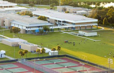 Okul çocukları spor parkındaki kampüs stadyumunda Amerikan futbolu oynuyorlar..