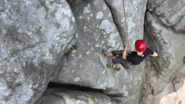 Genç adam kayalık dağın dik duvarından aşağı iniyor. Erkek tırmanışçı zorlu rotayı aşar. Ekstrem spor konseptine dalmak.