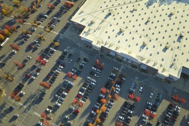 Hava manzaralı alışveriş merkezi ve park yerinde park yerleri ve yönler için çizgiler ve işaretler olan bir sürü renkli araba. Bir alışveriş merkezinin önünde araçlar için yer.