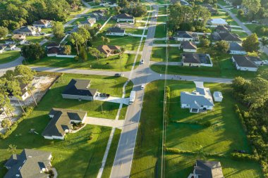 Aerial view of american small town in Florida with private homes between green palm trees and suburban streets in quiet residential area.