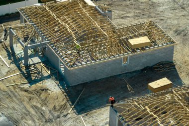 Florida 'nın banliyö bölgesinde inşaat halindeki ahşap çatı iskeleti yapısı olan bitmemiş bir ev üzerinde çalışan inşaatçıların hava görüntüsü..