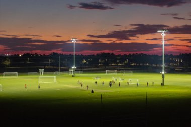 Gün batımında futbol oynayan gençlerle dolu bir stadyum. Aktif yaşam konsepti.