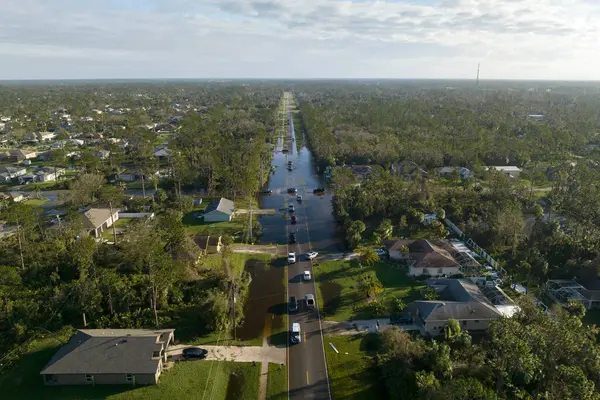 stock image Hurricahe fainfall flooded Florida road with evacuating cars and surrounded with water houses in suburban residential area.